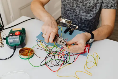 Hands preparing color-coded wiring for a new circuit