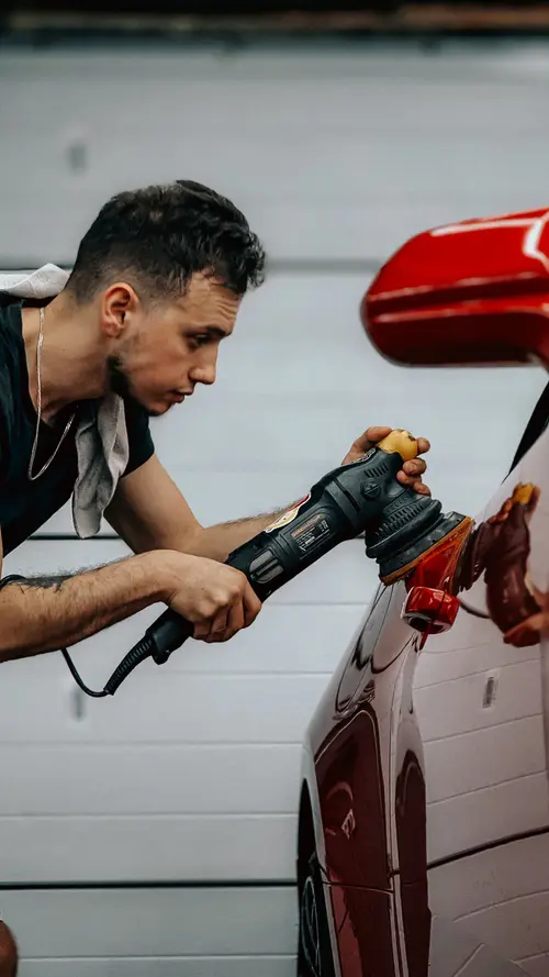 Technician machine-polishing a car panel to a deep gloss