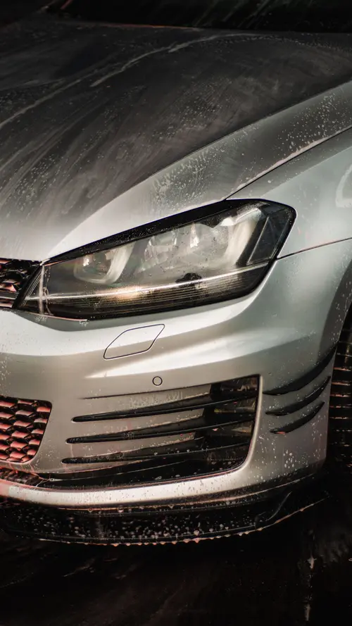 Close-up of a headlight and hood during a foam wash